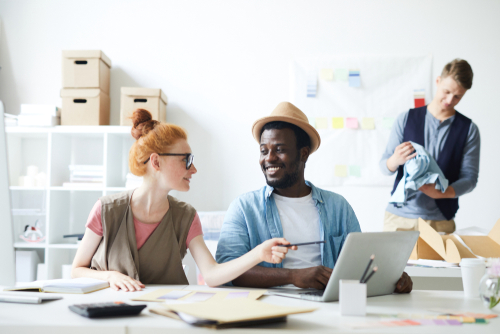 Young white woman discussing with her African colleague presentation on laptop