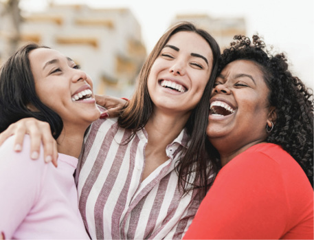 Happy latin women laughing and hugging each other outdoor in the city